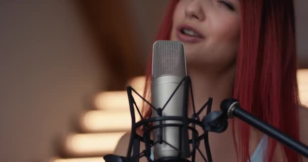 Красивая молодая женщина записывает песню в профессиональной студии. Сексуальная девушка позирует и танцует — стоковое видео
