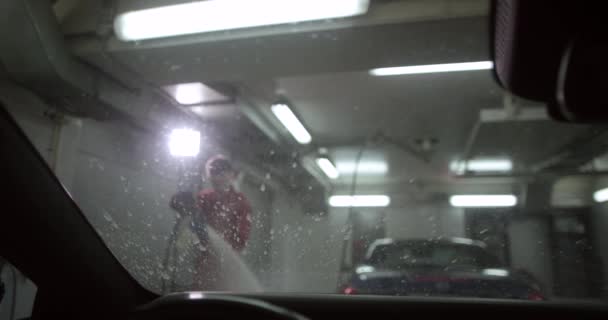 Innenaufnahme eines Mannes, der ein Auto mit Wasser und Schaum durch eine Waschanlage führt. — Stockvideo