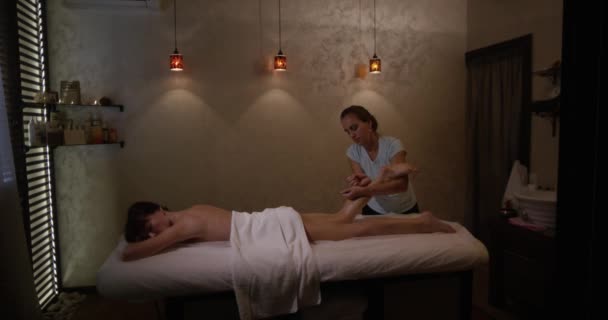 Wenige Schüsse. junge Frau mit Fußmassage im Schönheitssalon. Masseur knetet Fuß und Bein eines jungen schönen Mädchens in Zeitlupe. — Stockvideo