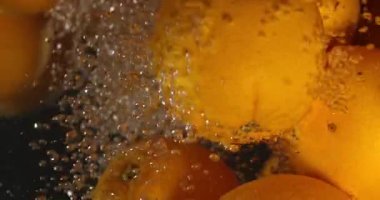 Turuncu damla siyah arka plan üzerine su altında. Taze turuncu meyve dalan ve su sıçramalarına su. Su hava kabarcıkları