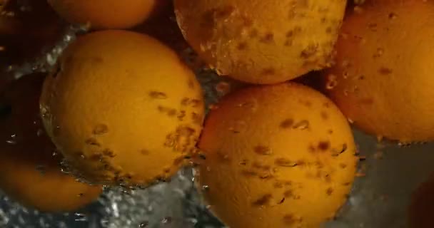 Orange Tropfen unter Wasser auf schwarzem Hintergrund. frische Orangenfrüchte tauchen ein und spritzen Wasser. Wasserluftblasen — Stockvideo
