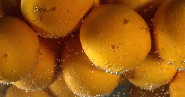 Orange droppar Under vatten på svart bakgrund. Orange frukt störta och stänk vatten. Vatten luftbubblor — Stockvideo