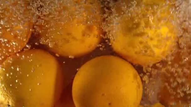 Pomarańczowy krople pod wodą na czarnym tle. Świeże owoce pomarańczowy tłoczenie i odrobiny wody. Pęcherzyki powietrza wody — Wideo stockowe