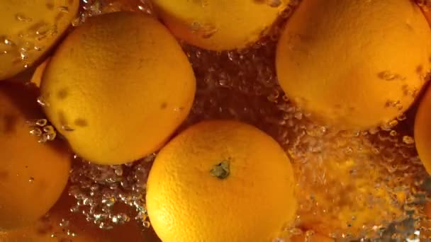 Orange droppar Under vatten på svart bakgrund. Orange frukt störta och stänk vatten. Vatten luftbubblor — Stockvideo