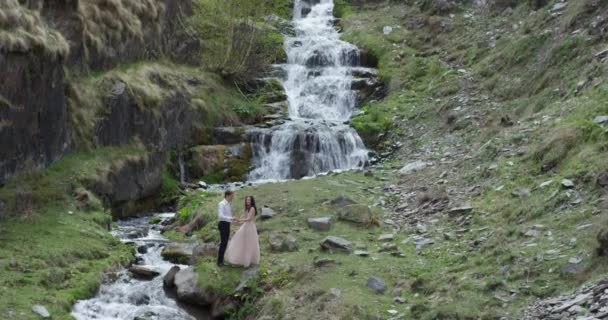 Молодая красивая супружеская пара, стоящая у водопада. В день свадьбы. Медленное движение — стоковое видео