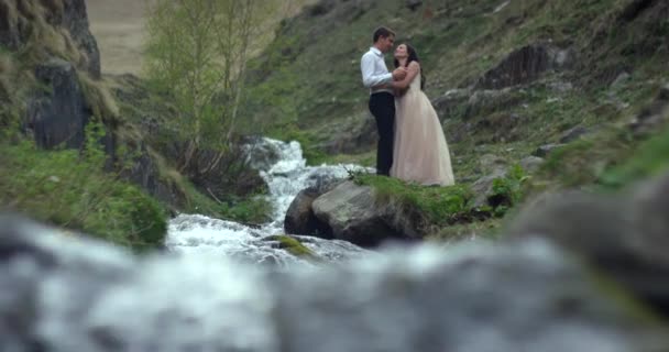 Pasangan pengantin muda yang cantik berdiri di dekat air terjun. Hari pernikahan. Gerakan lambat — Stok Video