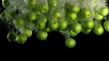 Yavaş çekim: yeşil elma düşer ve yüzen su, siyah arka planda