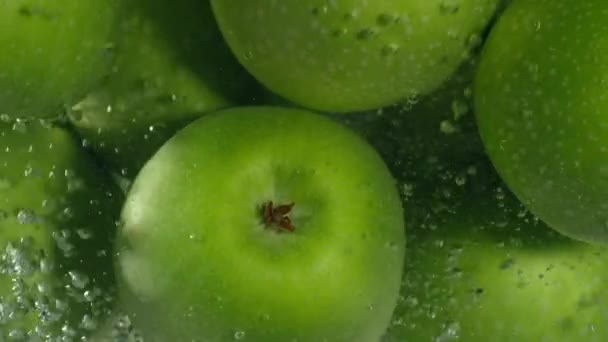 Manzanas verdes caen en el agua sobre fondo negro, super cámara lenta — Vídeo de stock