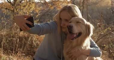 Güzel bir kadın onu labrador retriever köpek ile bir selfie. Sarışın kız parkta onun smartphone bir selfie yapma.