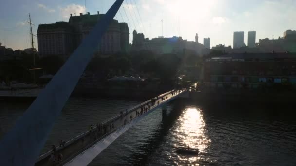 Vista aérea do drone da ponte pedestre das mulheres, Puente de la Mujer em um porto de Puerte Madero no por do sol. Buenos Aires, Argentina . — Vídeo de Stock