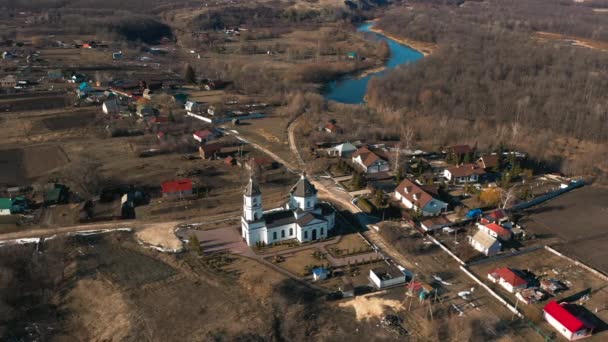 Vista aérea de uma pequena aldeia com uma igreja e rio. Campo na Rússia. Hora da Primavera . — Vídeo de Stock