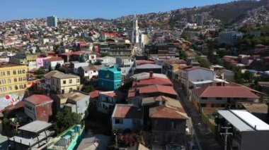 Tarihi liman kentinin tepelerinde rengarenk dekore edilmiş evlerin havadan drone görünümü. Arka planda Iglesia de Los Doce Apostoles Kilisesi. Valparaiso, Şili