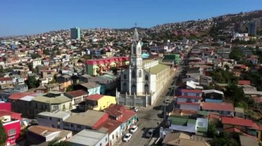 Tarihi liman kentinin tepelerinde rengarenk dekore edilmiş evlerin havadan drone görünümü. Arka planda Iglesia de Los Doce Apostoles Kilisesi. Valparaiso, Şili