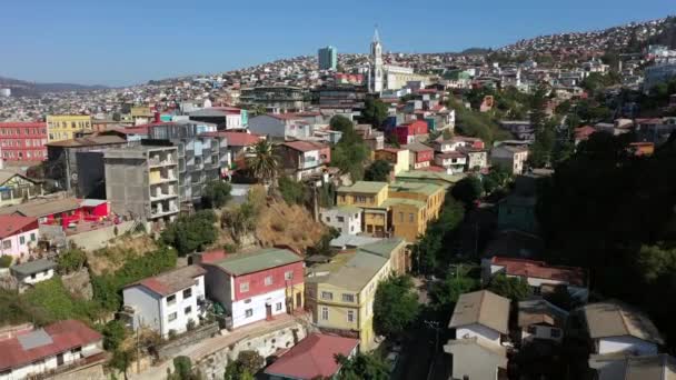 Aerial drone view of Colourfully decorated houses on the hills of the historic port city. Iglesia de los Doce Apostoles church on the background. Valparaiso, Chile — Stock Video