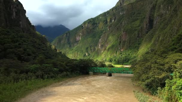 Εναέρια προβολή του πράσινου τοπίου με μια γέφυρα πάνω από ένα ποτάμι κοντά στο Μάτσου Πίτσου, Περού — Αρχείο Βίντεο