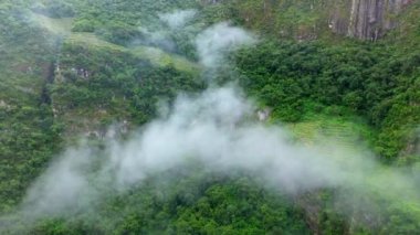 Andes yeşil orman Dağları bulutlar üzerinden hava drone uçuş. Peru, Machu Picchu 'ya yakın. Arka planda İnka terasları.