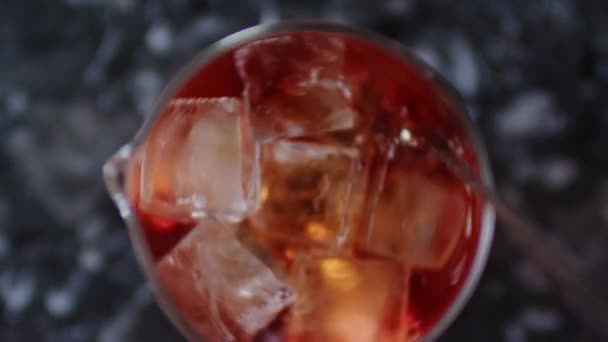 Top uitzicht van ijsblokjes mengen in een glas met een drankje. Barman met behulp van een lange metalen lepel. Close-up shot op 6k rode camera. — Stockvideo