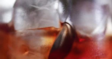 Buz küpleri bir bardakta içkiyle karışıyor. Barmen uzun metal bir kaşık kullanıyor. 6k Kırmızı kamerada çekimi kapatın.