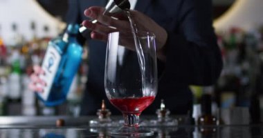 Barmen negroni kokteyli hazırlamak için karıştırma camı içine cin döküyor. 6k Kırmızı kamerada çekimi kapatın.