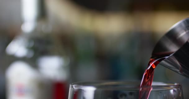 Closeup of bartender pouring gin into the mixing glass to prepare a negroni cocktail. — Stock Video