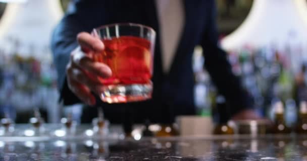 Barman glijden ouderwetse Negroni cocktail naar een klant. Close-up shot op 6k rode camera. — Stockvideo