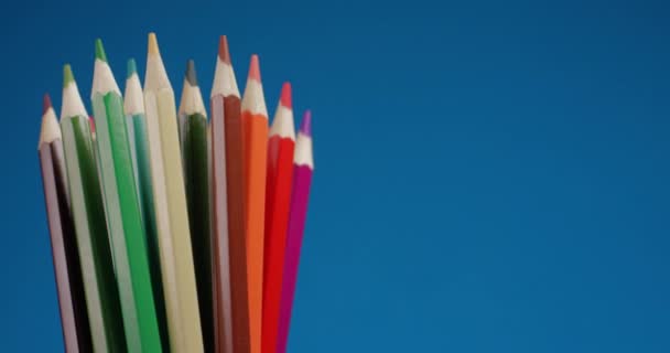 Conjunto de lápices multicolores girando sobre una pantalla azul, fondo cromado. Vista de cerca extrema, filmada con la cámara RED 6K — Vídeo de stock