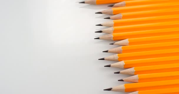 Žluté potažené tužky sklouzávající na bílém pozadí. Záběr zblízka, záběr na červenou 6k kameru — Stock video
