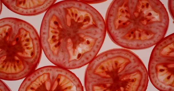 Fette di pomodoro rosso fresco ruotanti su uno sfondo bianco brillante. Vista dall'alto, ripresa sulla fotocamera RED 6K — Video Stock