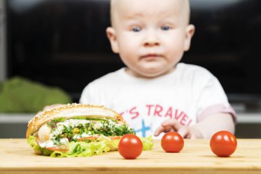 Litlle bebek beyaz çocuk bir lezzetli sosisli kiraz domates yakın tablo yeşil salata ile çalmaya çalışıyor