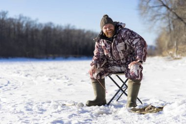 Sakallı Avrupa adam o Nehri üzerinde buz delikten kış balık tutma sırasında gülümseyen gündüz 