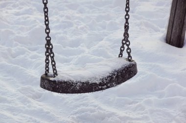 Kışın kar yağarken boş salıncak.