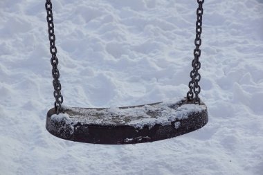 Kışın kar yağarken boş salıncak.