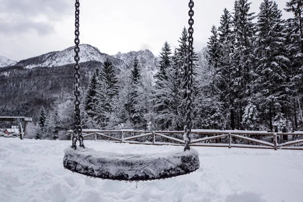 Kışın kar yağarken boş salıncak.