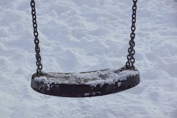 Kışın kar yağarken boş salıncak.