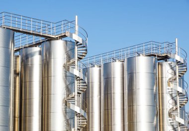 Arka planda mavi gökyüzü ile gümüş şarap siloları