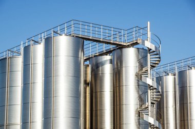 Arka planda mavi gökyüzü ile gümüş şarap siloları