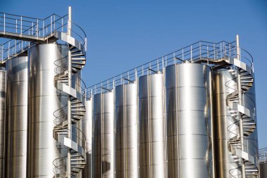 Arka planda mavi gökyüzü ile gümüş şarap siloları