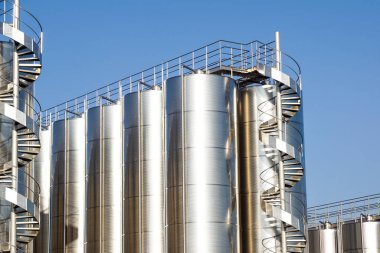 Arka planda mavi gökyüzü ile gümüş şarap siloları