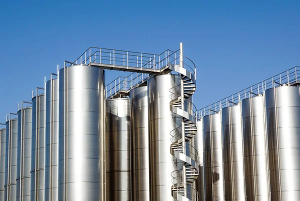 Arka planda mavi gökyüzü ile gümüş şarap siloları