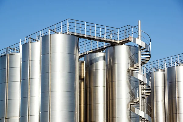 Arka planda mavi gökyüzü ile gümüş şarap siloları