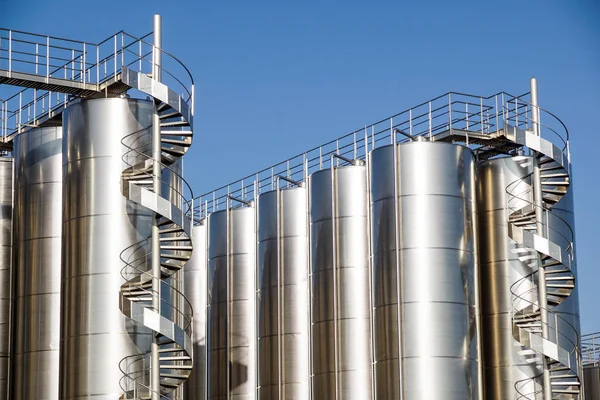 Arka planda mavi gökyüzü ile gümüş şarap siloları