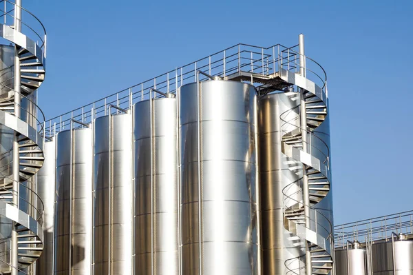 Arka planda mavi gökyüzü ile gümüş şarap siloları