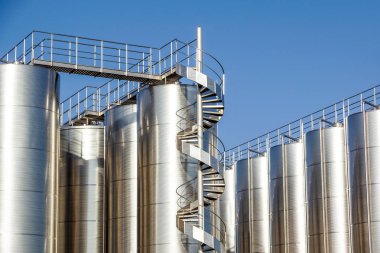 Arka planda mavi gökyüzü ile gümüş şarap siloları