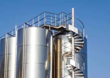 Arka planda mavi gökyüzü ile gümüş şarap siloları