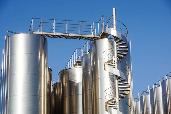 Arka planda mavi gökyüzü ile gümüş şarap siloları
