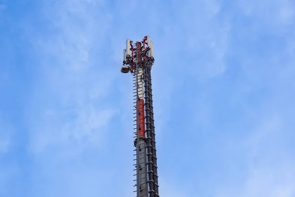 Torre de antena de telecomunicação e repetidor de sinal de comunicação móvel com céu azul, sobre a construção — Fotografia de Stock