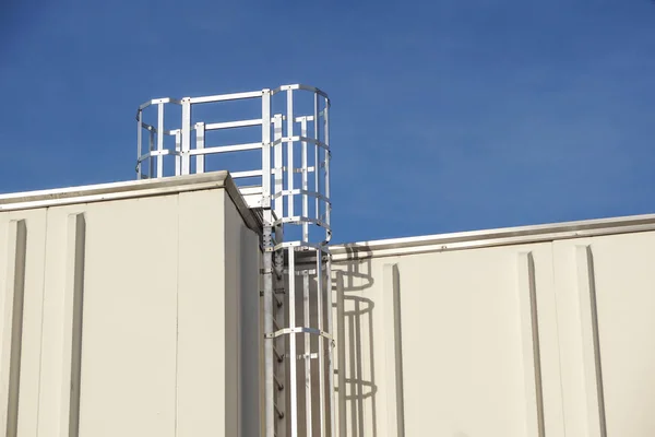 Steel ladder with protection, attached to an industrial, production hall or building.