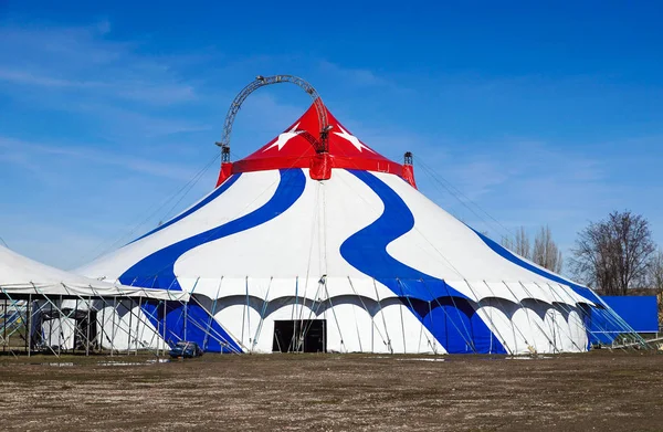 A blue striped circus tent in green nature.