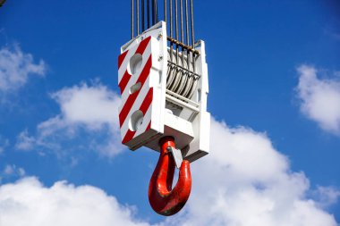 Crane hook with red and white stripes hanging, blue sky in background clipart