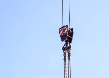 Kırmızı ve beyaz çizgili turna kancası asılı, mavi gökyüzü arka planda .